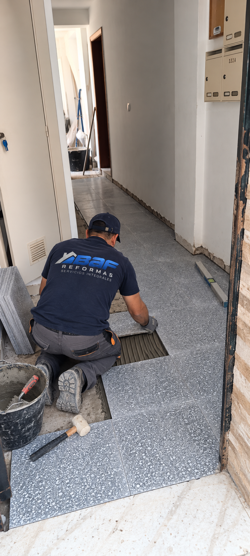 Profesional de BAF Reformas colocando baldosas de terrazo gris con mortero