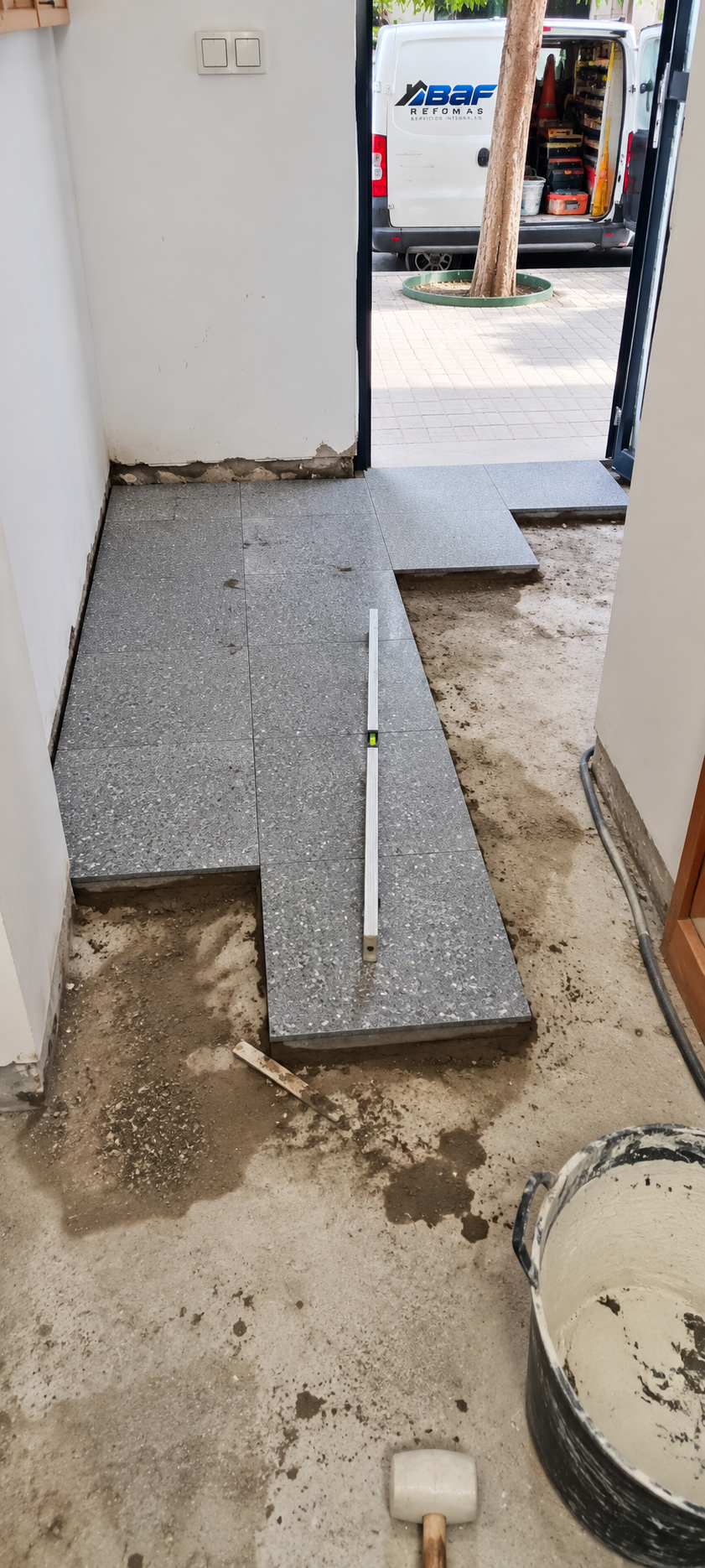 Baldosas de terrazo gris colocadas por tramos durante la renovación de un pasillo