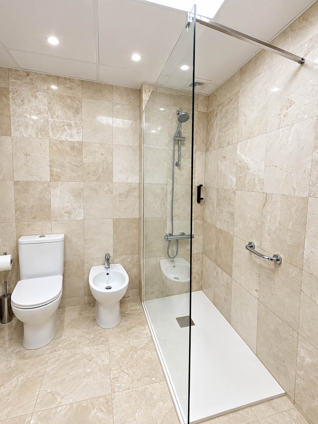 Baño completo con ducha, mampara transparente y revestimiento cerámico efecto mármol